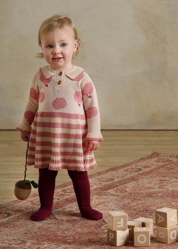 Child wearing a pink and white striped cotton dress with apple pattern