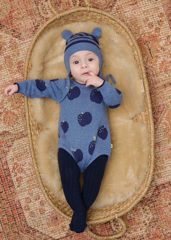 Baby in a blue cotton romper with apple pattern and navy tights