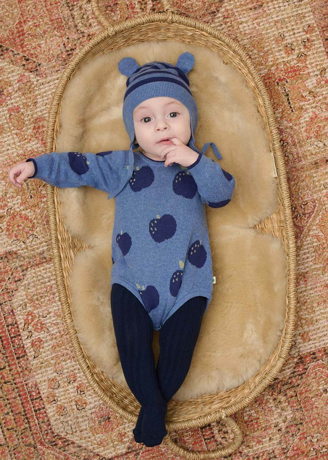 Baby in a blue cotton romper with apple pattern and navy tights