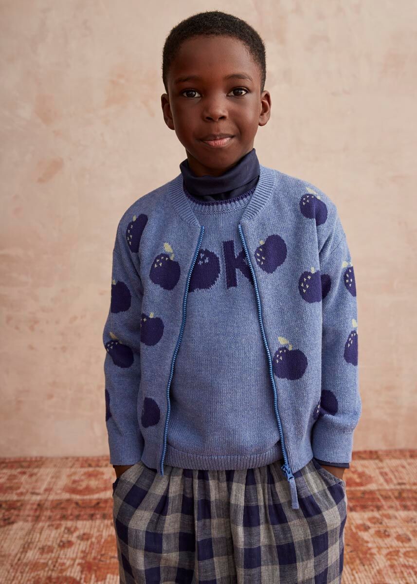 Child wearing a blue cotton cardigan with an apple pattern