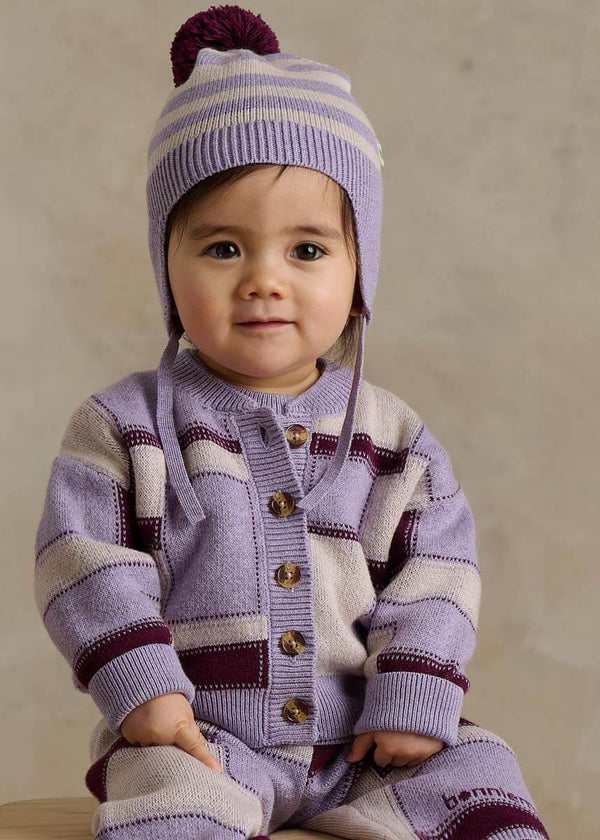 Child wearing a purple striped outfit with a matching knit hat 