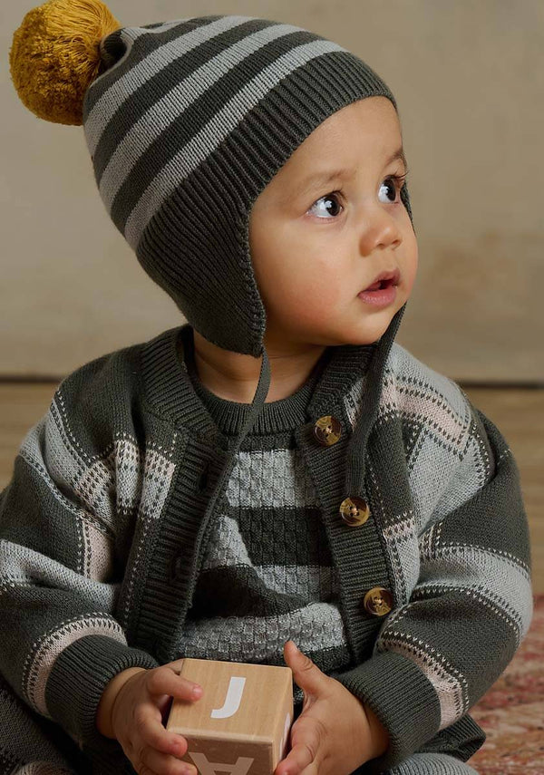 Child wearing a green striped knit hat and cardigan 