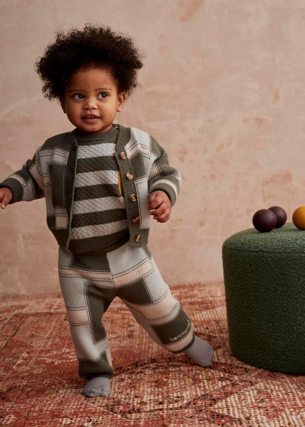 Child wearing a green knit striped jumper, cardigan and pants set