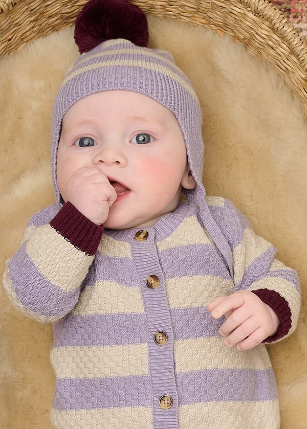 Baby wearing a purple striped playsuit and hat with a pom-pom
