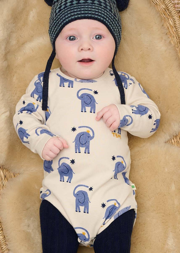 Baby wearing a white cotton onesie with blue elephant patterns 
