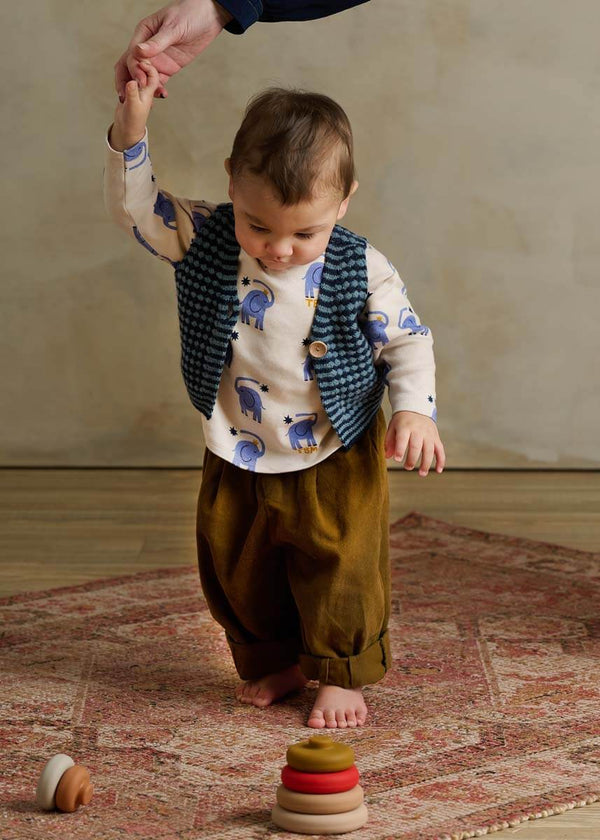 Child wearing blue knitted vest and olive trousers