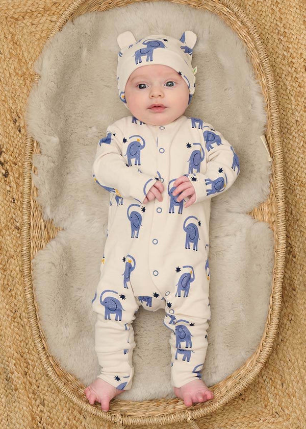 Baby in a white cotton onesie with blue animal patterns and a matching hat