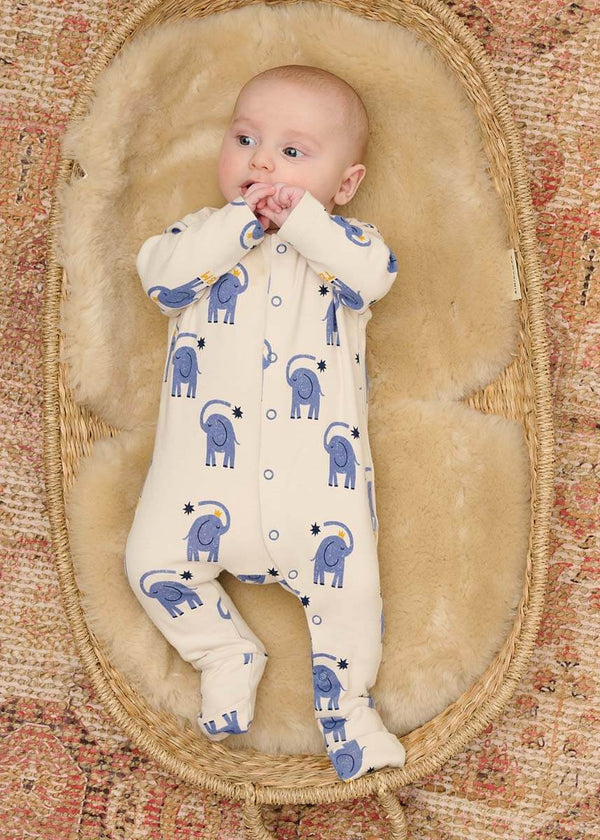 Baby in a white cotton onesie with blue elephant patterns 