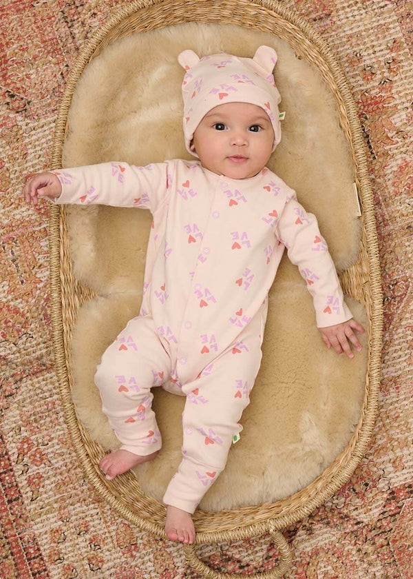 Baby in a pink cotton onesie and hat with a heart pattern
