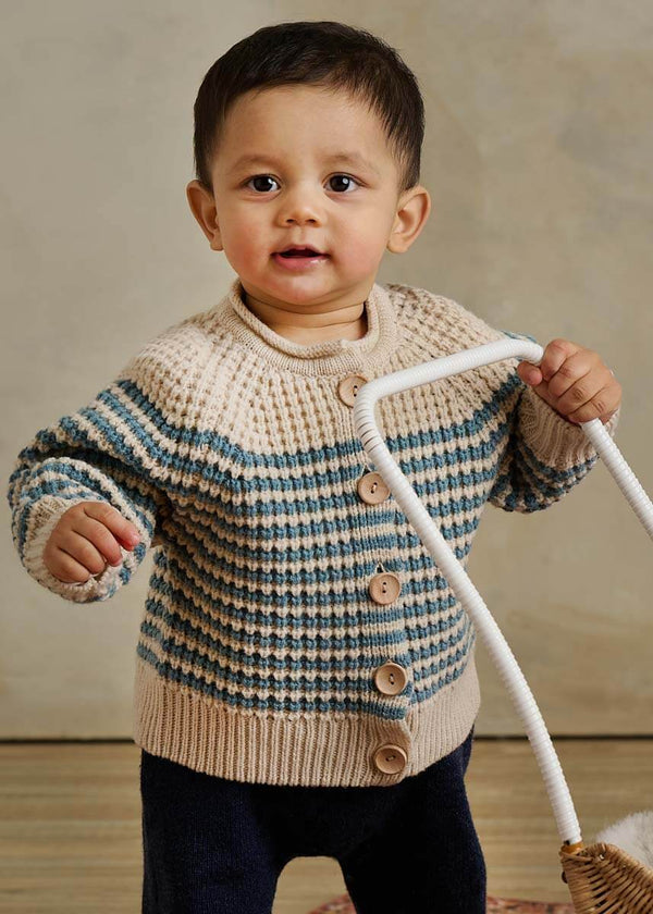 Child wearing a striped cream and blue sweater 